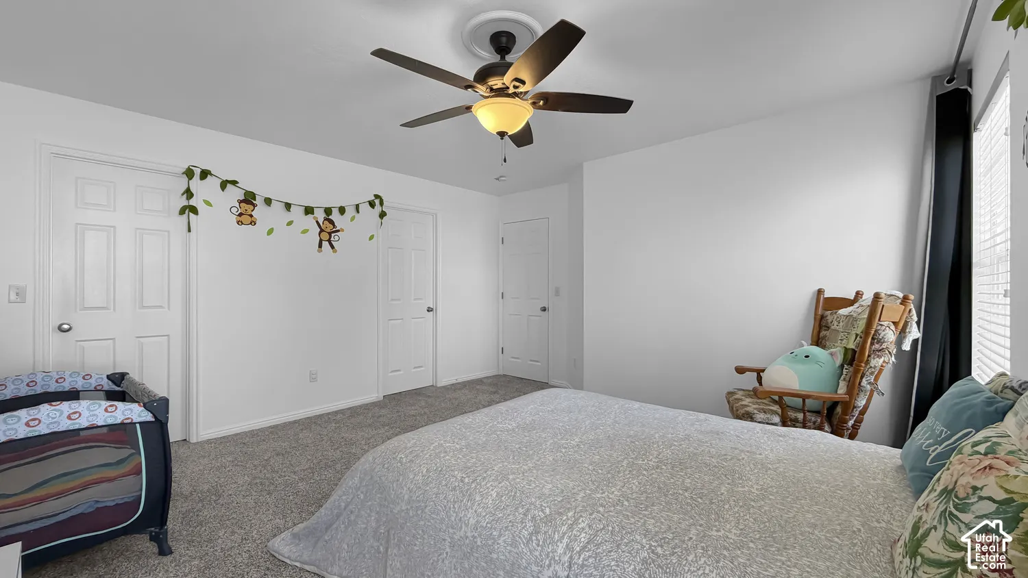 Ceiling fan with integrated lighting, window with blinds, panel doors, and grey carpeting