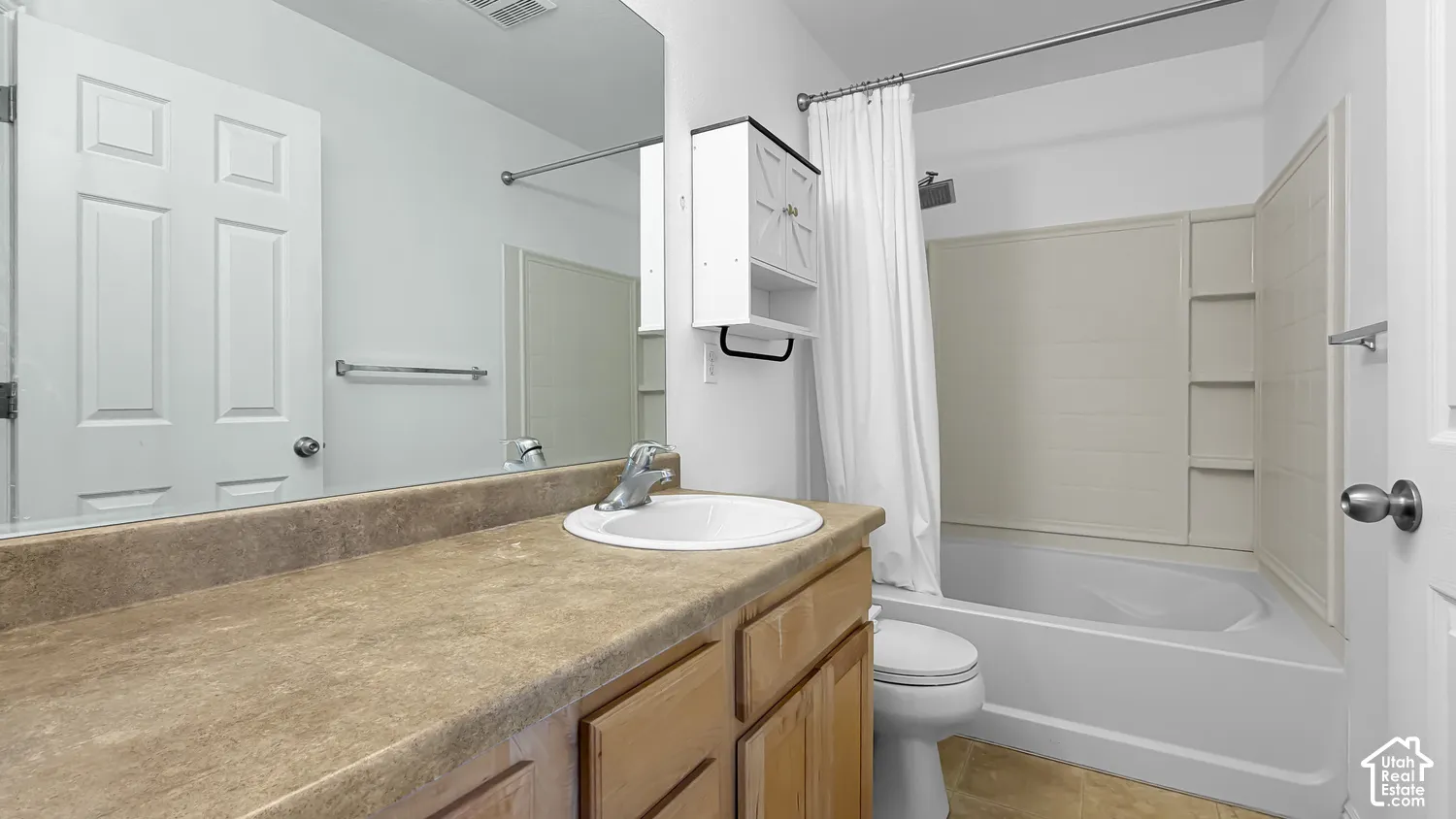 Bathroom featuring a single vanity with wood-finish cabinetry, a white basin, and a combination shower-tub with a white surround