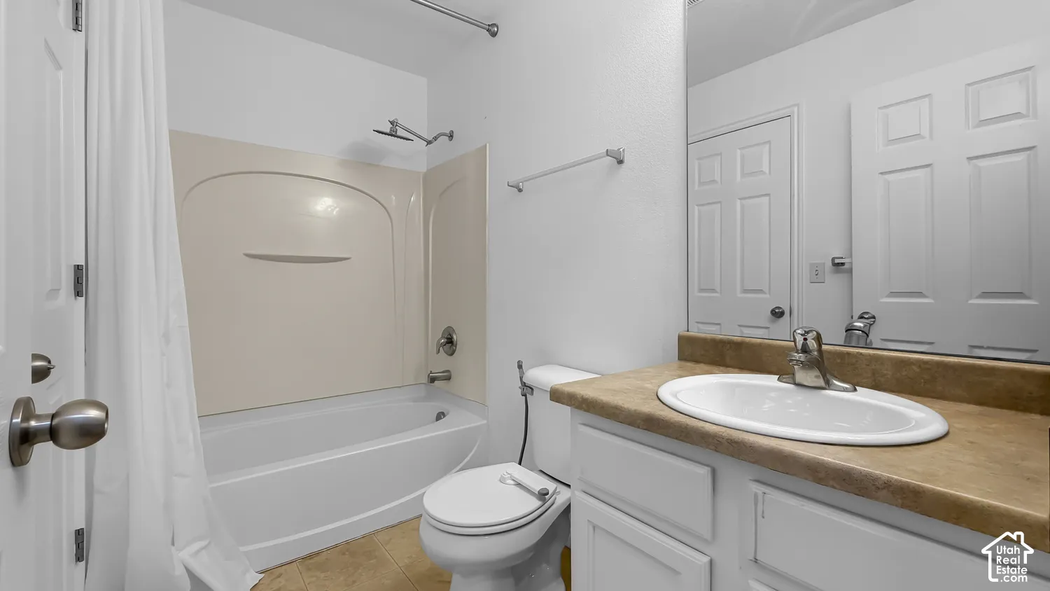 Full bathroom featuring a white tub, shower with light-toned surround, a vanity with a drop-in sink, and a large mirror