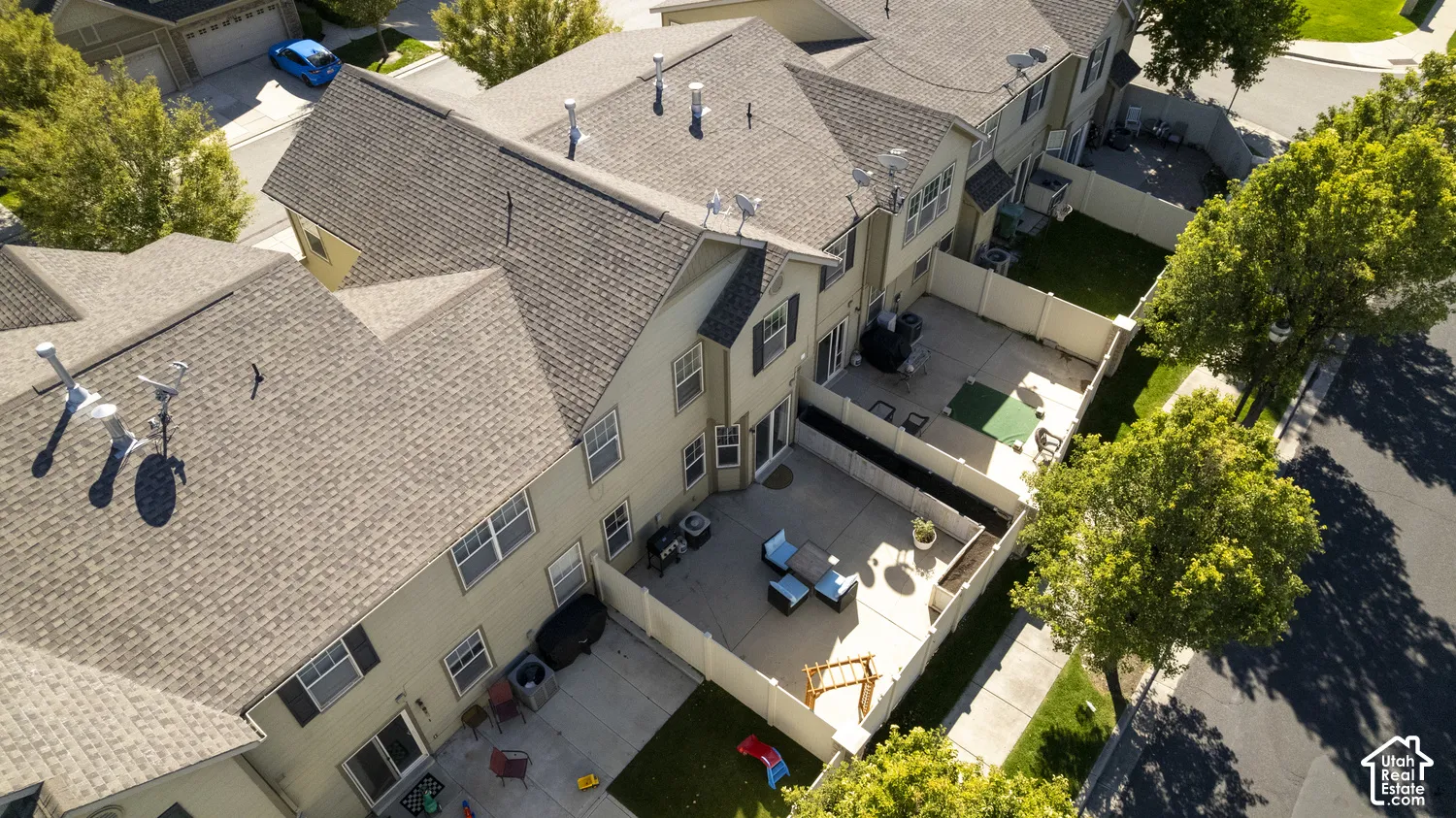 Rear exterior featuring multiple windows, a sliding glass door, a private concrete patio, and a fenced yard with grass