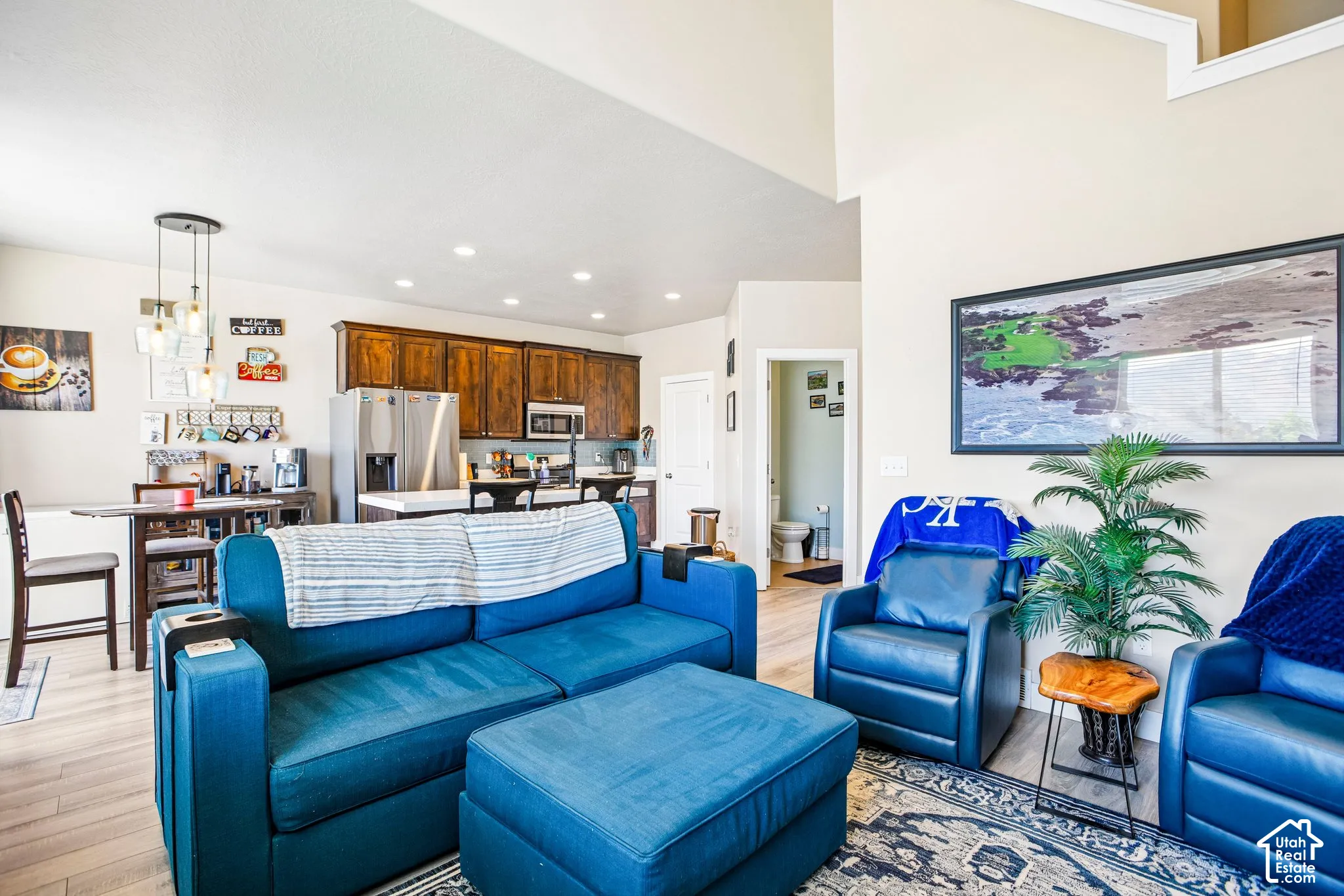 Two-story living area with wood-finish flooring, recessed lighting, and a modern chandelier