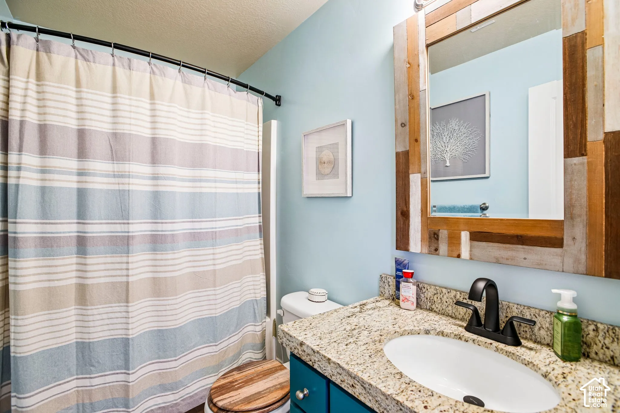Vanity with a granite countertop, undermount sink, and matte black faucet