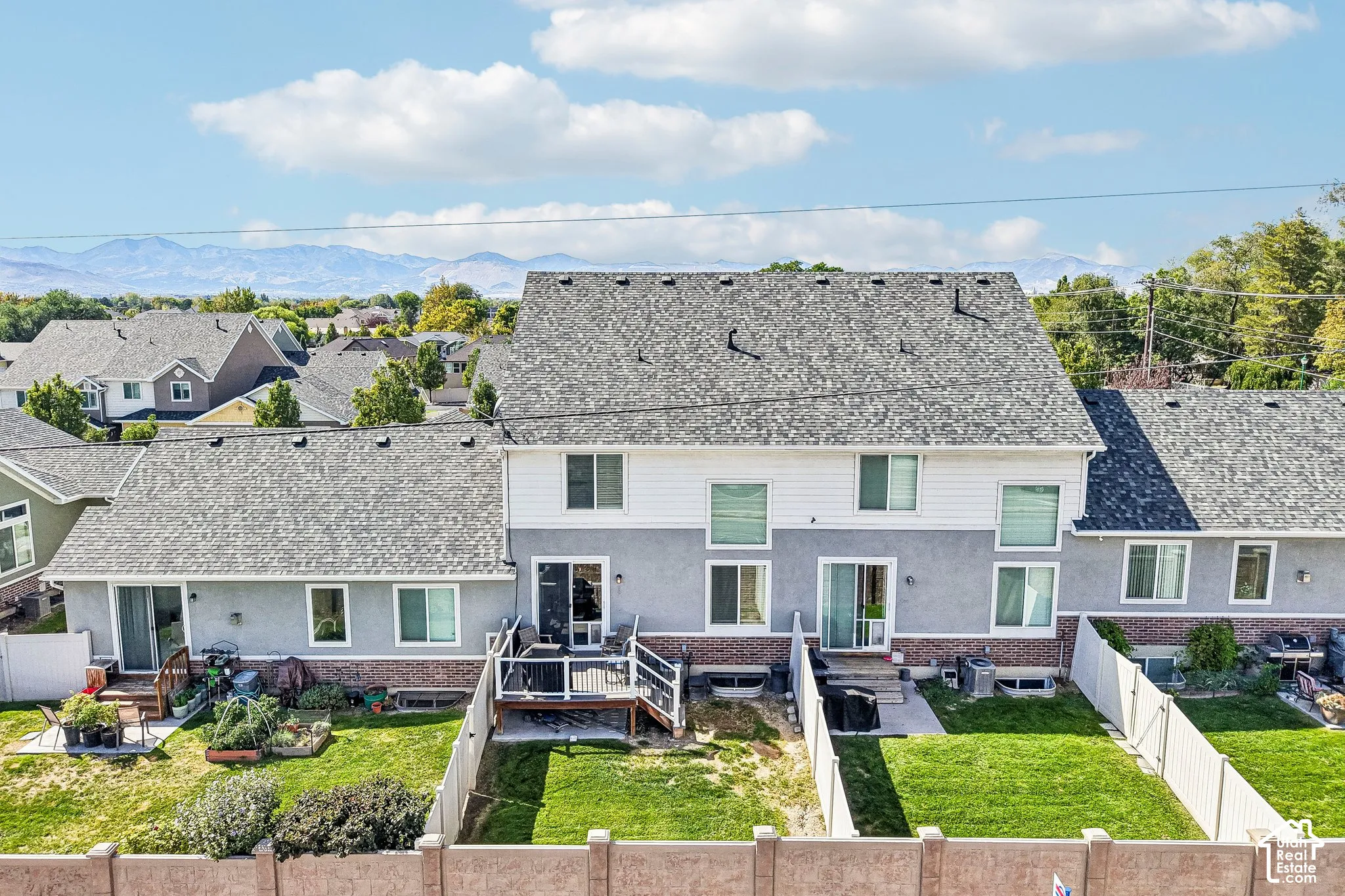 Expansive backyard featuring a manicured lawn, wood deck, and white privacy fencing