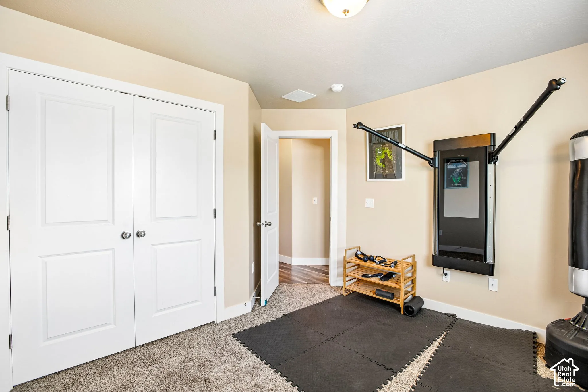 Carpeted room with double bi-fold doors, neutral painted walls, and a ceiling-mounted light fixture