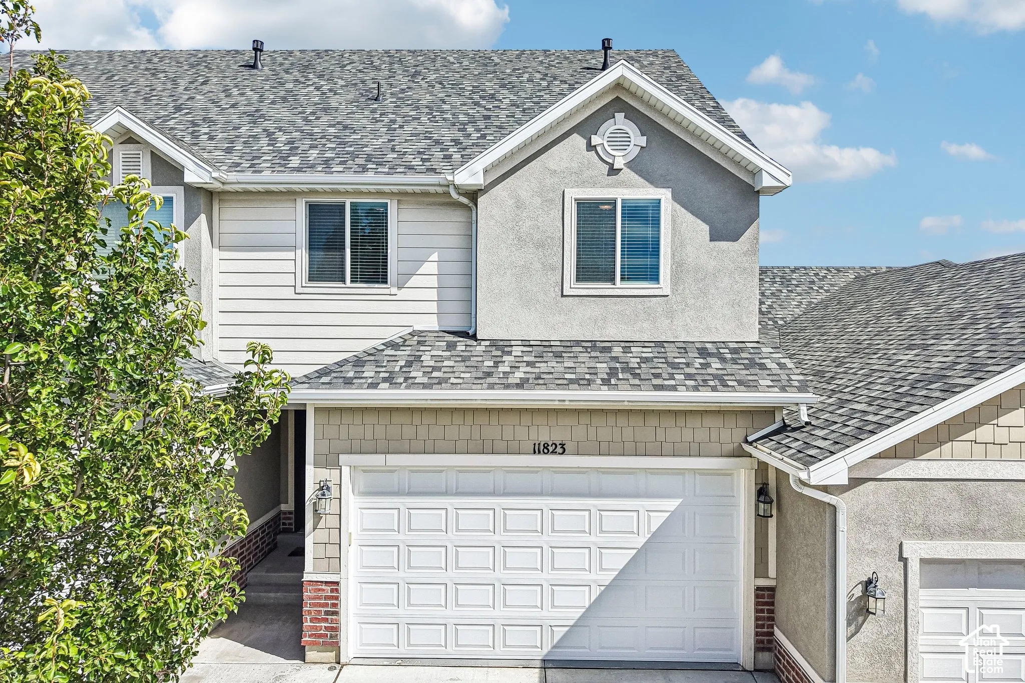 Multi-story residence featuring composite shingle roofing, stucco siding, horizontal siding, and a paneled garage door