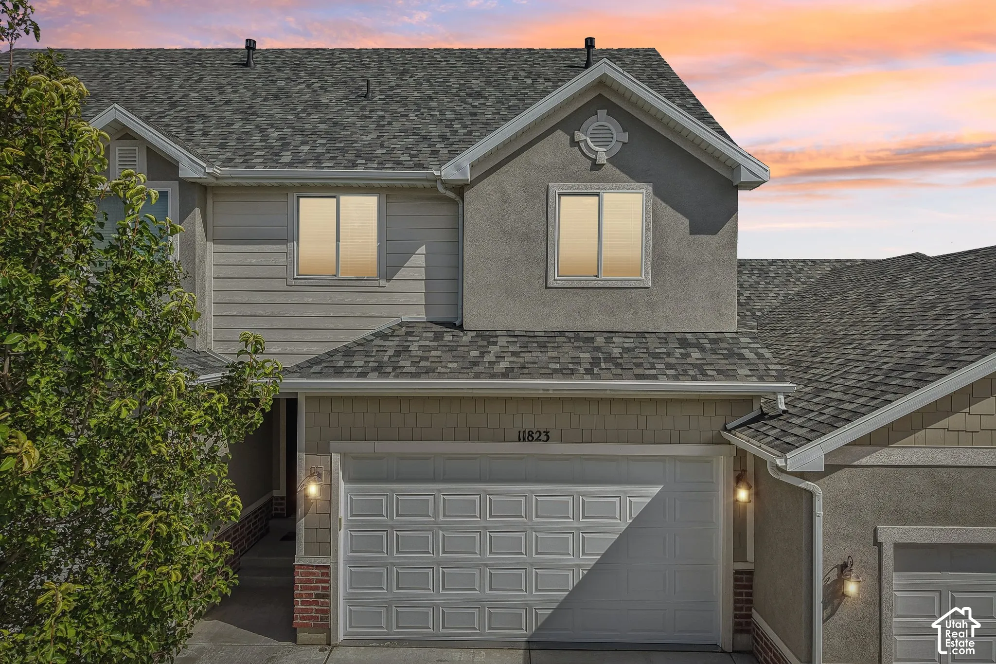 Multi-level exterior featuring a two-car garage, gray shingle roofing, and mixed siding