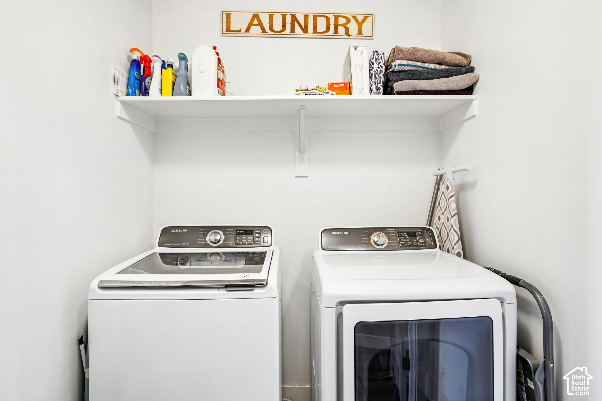 Laundry area featuring a top-load washing machine, front-load dryer, and an overhead storage shelf