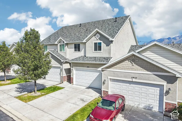 Stucco and siding exterior with brick accents, asphalt shingle roofing, and attached garages