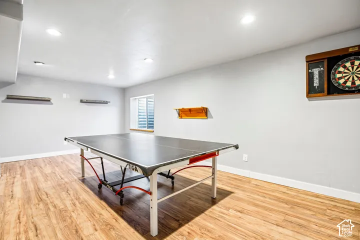 Recessed lighting illuminates the spacious room with wood-finish flooring