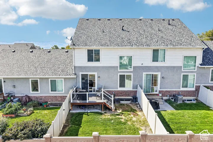 Rear exterior featuring a multi-level deck, sliding glass doors, white vinyl fencing, and a shingled roof