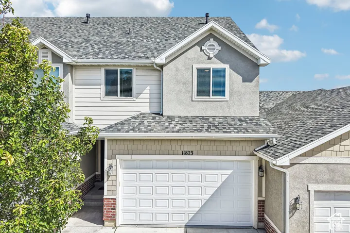 Multi-story residence featuring composite shingle roofing, stucco siding, horizontal siding, and a paneled garage door