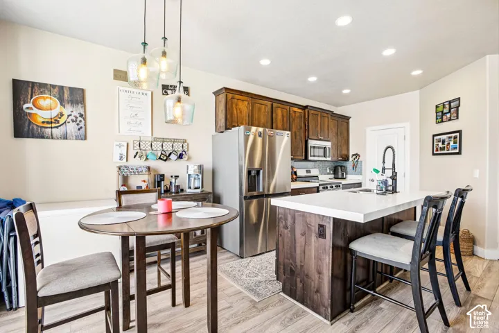 Kitchen featuring stainless steel appliances, dark wood cabinetry, white countertops, and a tile backsplash