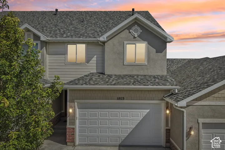 Multi-level exterior featuring a two-car garage, gray shingle roofing, and mixed siding