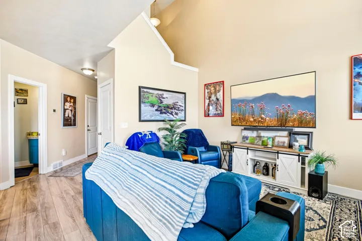 High vaulted ceilings, wood-finish flooring, recessed lighting, white trim, and a built-in media console