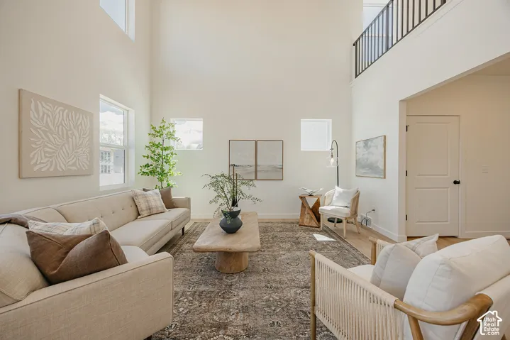 Vaulted ceilings with upper windows, light wood-finish flooring, and a black wrought iron railing