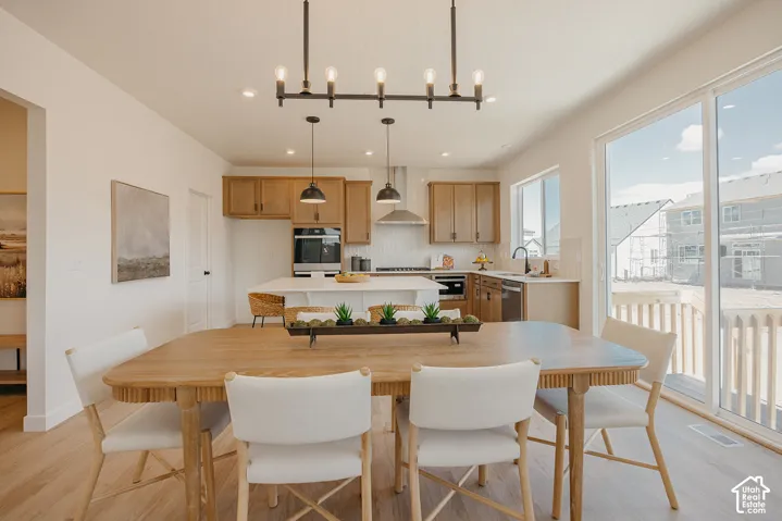 Open-concept dining area with wood-finish flooring, a contemporary linear chandelier, and sliding glass doors