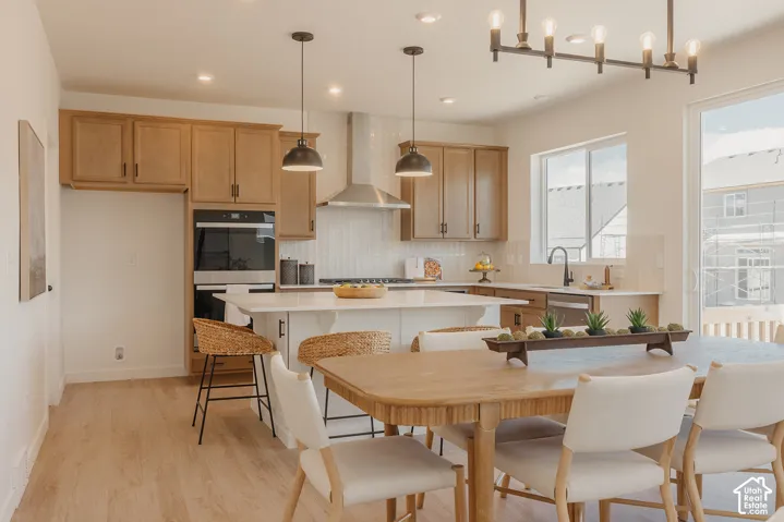 Kitchen featuring light wood-finish cabinetry, a central island with a white countertop, stainless steel appliances, and a tiled backsplash