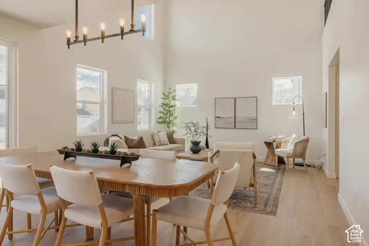 Vaulted ceiling with skylights, multiple windows providing natural illumination, wood-finish flooring, and a linear chandelier