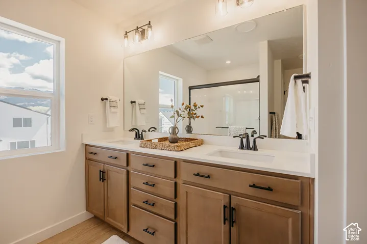 Double vanity with white countertops, wood-finish cabinetry, and black hardware