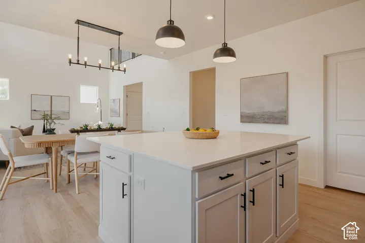 Kitchen island with a light-toned countertop, light-colored cabinetry, and black hardware