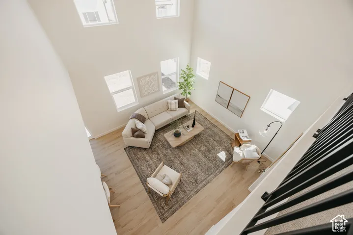 Two-story living area with high ceilings, wood-finish flooring, and multiple windows