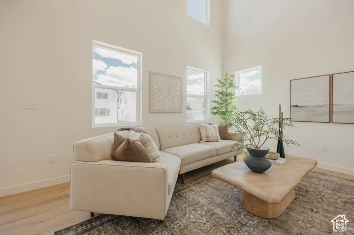High ceilings with upper windows, wood-finish flooring, multiple windows, and a neutral color palette