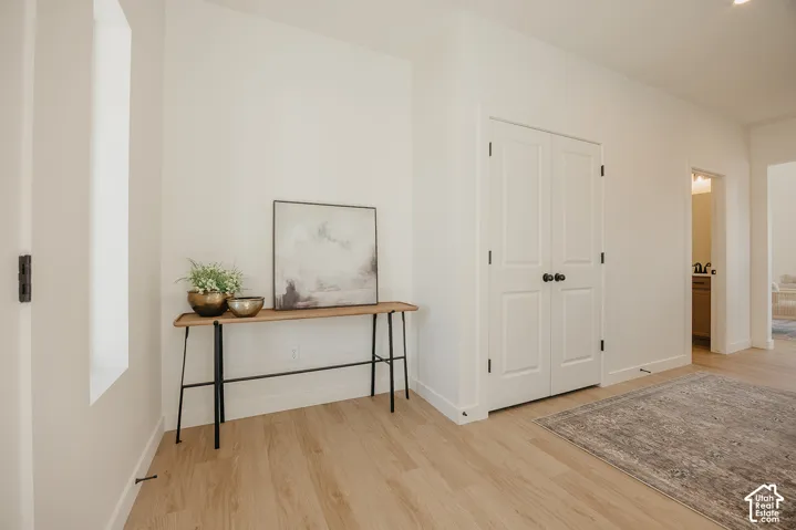 Recessed lighting, light wood-finish flooring, white walls, and a white paneled door
