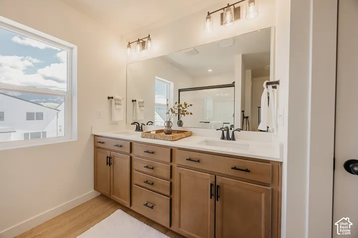 Dual vanity with wood-finish cabinetry, white countertop, and matte black fixtures