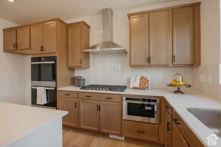 Kitchen featuring wood-finish cabinetry, stainless steel appliances, a gas cooktop, and light-toned countertops
