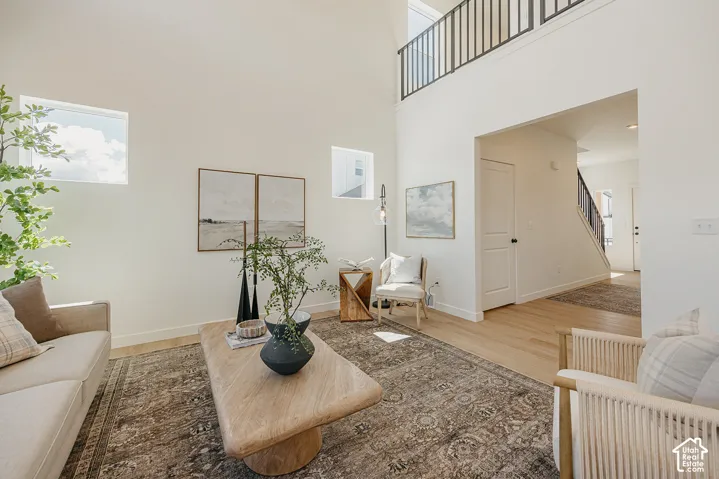 Vaulted ceilings with abundant natural light, light wood-finish flooring, and a second-story interior balcony with black railings