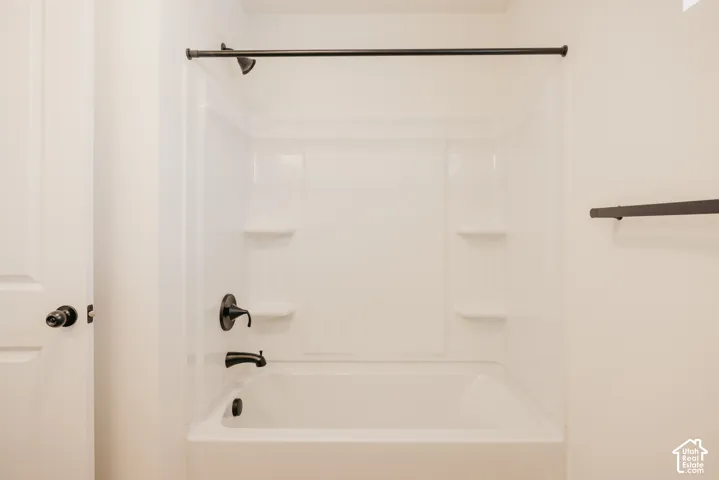 White acrylic tub and shower combination with integrated shelving, matte black fixtures, and a coordinating matte black shower rod