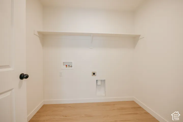 Utility area with wood-finish flooring, a built-in shelf, and appliance hookups