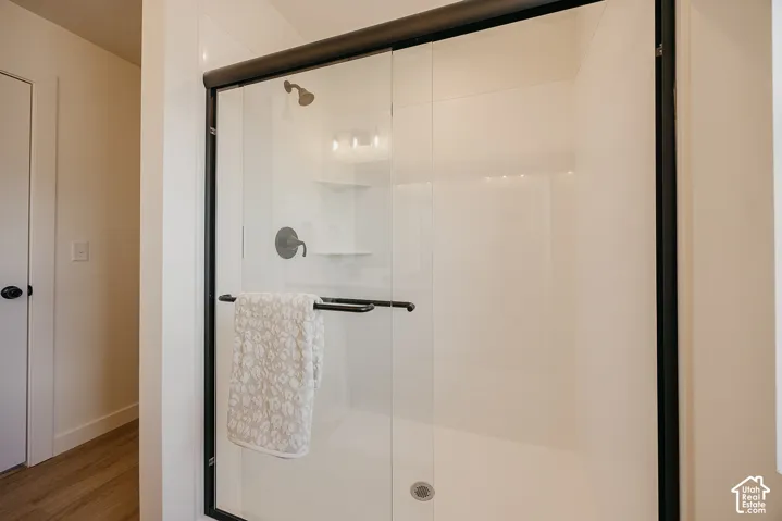 Frameless glass shower enclosure with matte black hardware, integrated shelving, and a rain showerhead