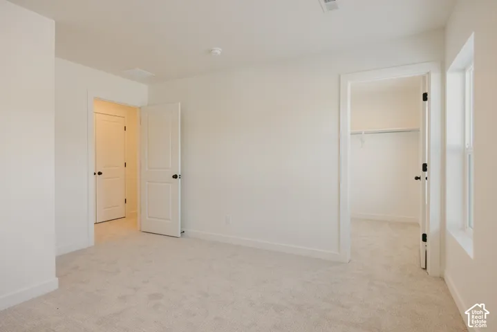 Carpeted room with white walls, a white trim window, and interior doors with black hardware