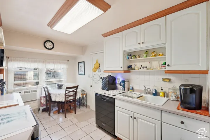 Kitchen featuring white cabinetry with wood trim, a tiled backsplash, and a built-in dishwasher