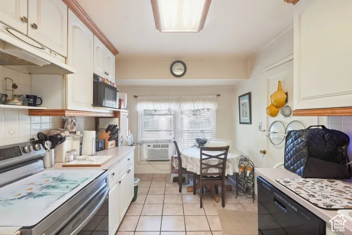Kitchen featuring white cabinetry, a built-in microwave, tiled flooring, and a window with natural light