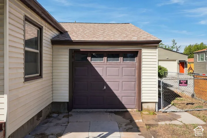 Attached garage with a panel-style door, composite shingles, and vinyl siding