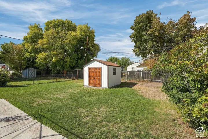 Expansive backyard featuring a storage shed with wood-finish double doors and a second storage shed