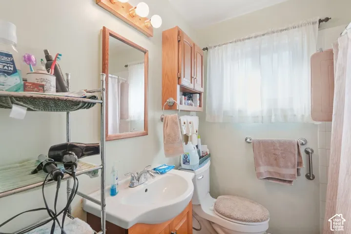 Bathroom featuring a vanity with an integrated sink, a rectangular framed mirror, a wall-mounted light fixture, and a window with natural light