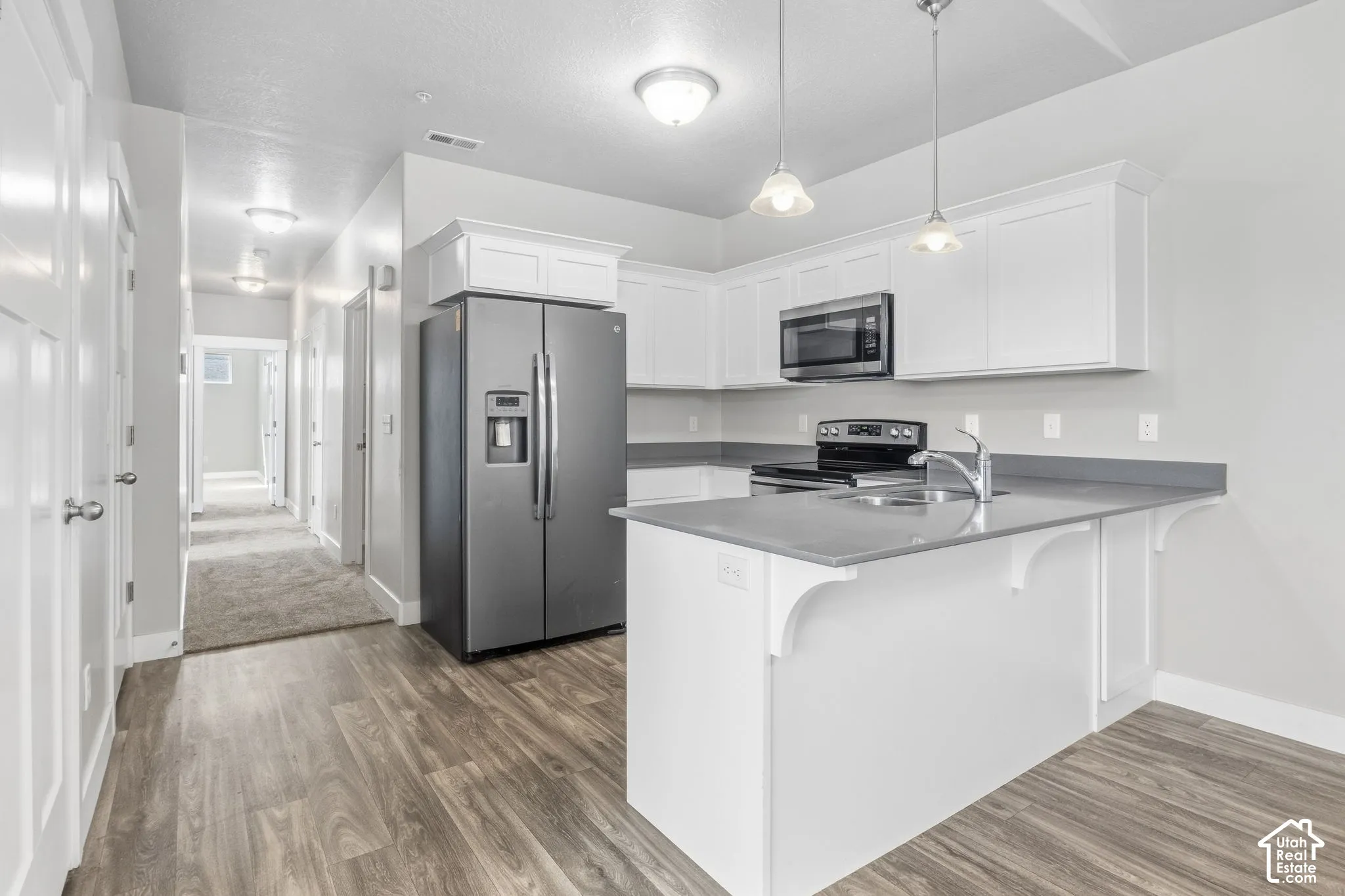Kitchen featuring white cabinetry, a stainless steel microwave, and gray countertops