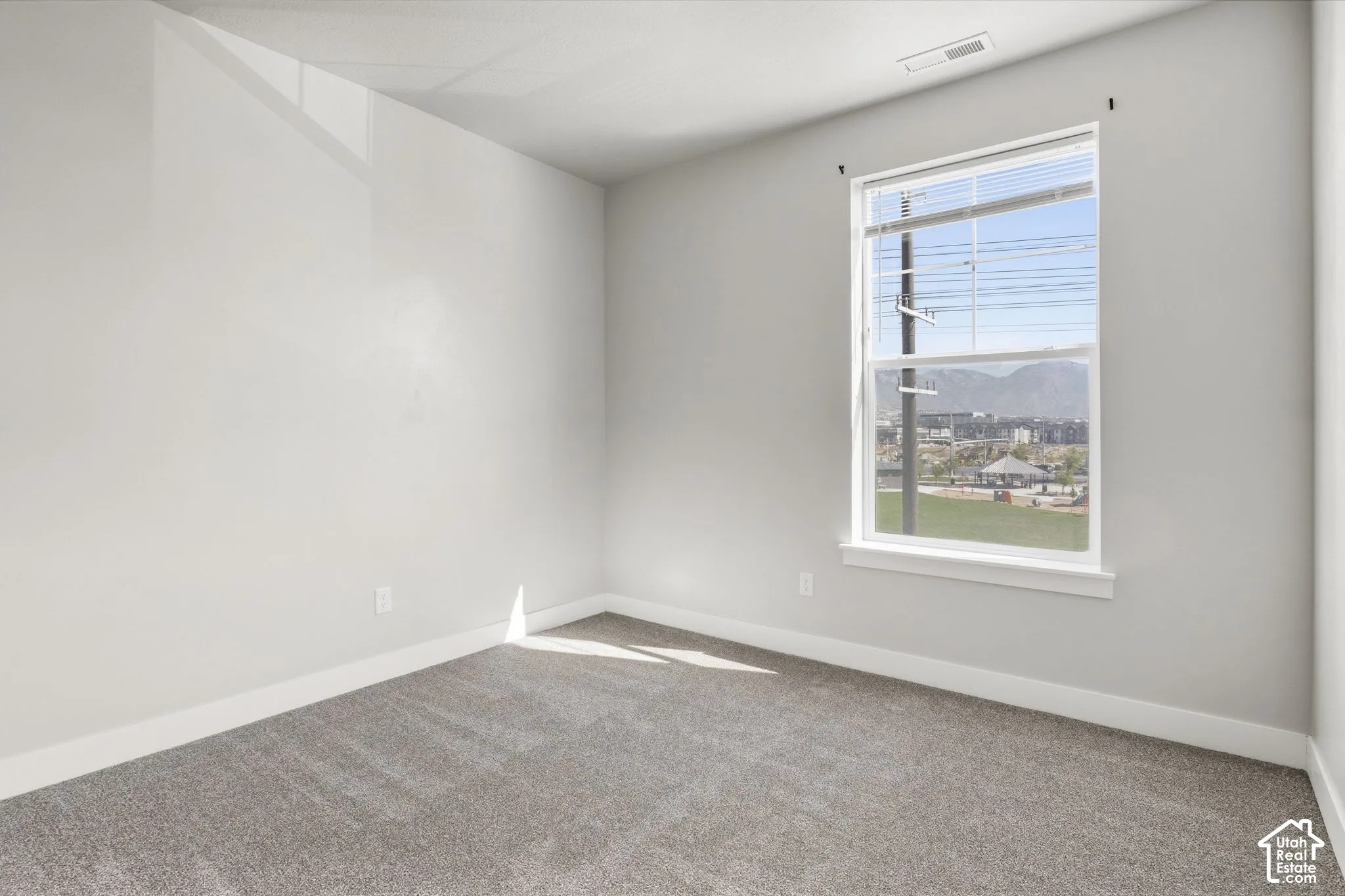 Neutral wall finishes, grey carpet flooring, and a double-hung window with white trim