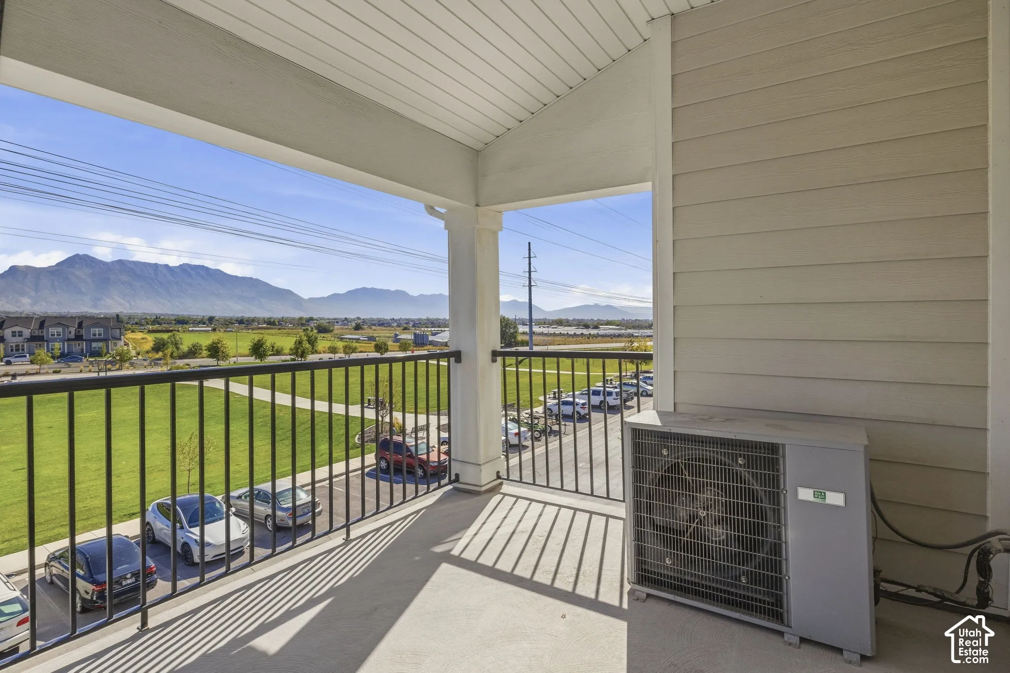 Covered balcony with a concrete floor, black metal railing, and mountain scenery