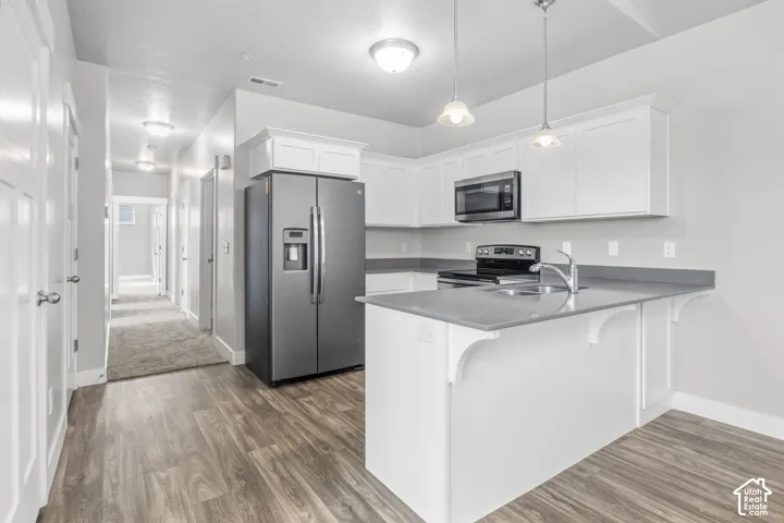 Kitchen featuring white cabinetry, a stainless steel microwave, and gray countertops