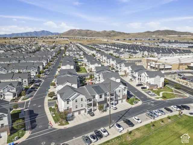 New construction residential development featuring multi-story residences with attached garages, paved streets, and a mountain backdrop