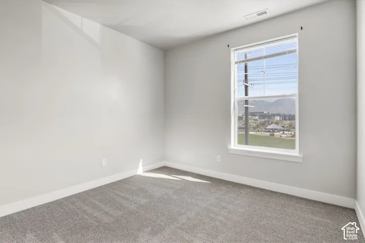 Neutral wall finishes, grey carpet flooring, and a double-hung window with white trim