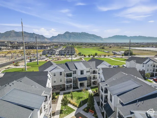 Modern multi-story buildings featuring balconies, a central courtyard with pathways, and paved parking areas