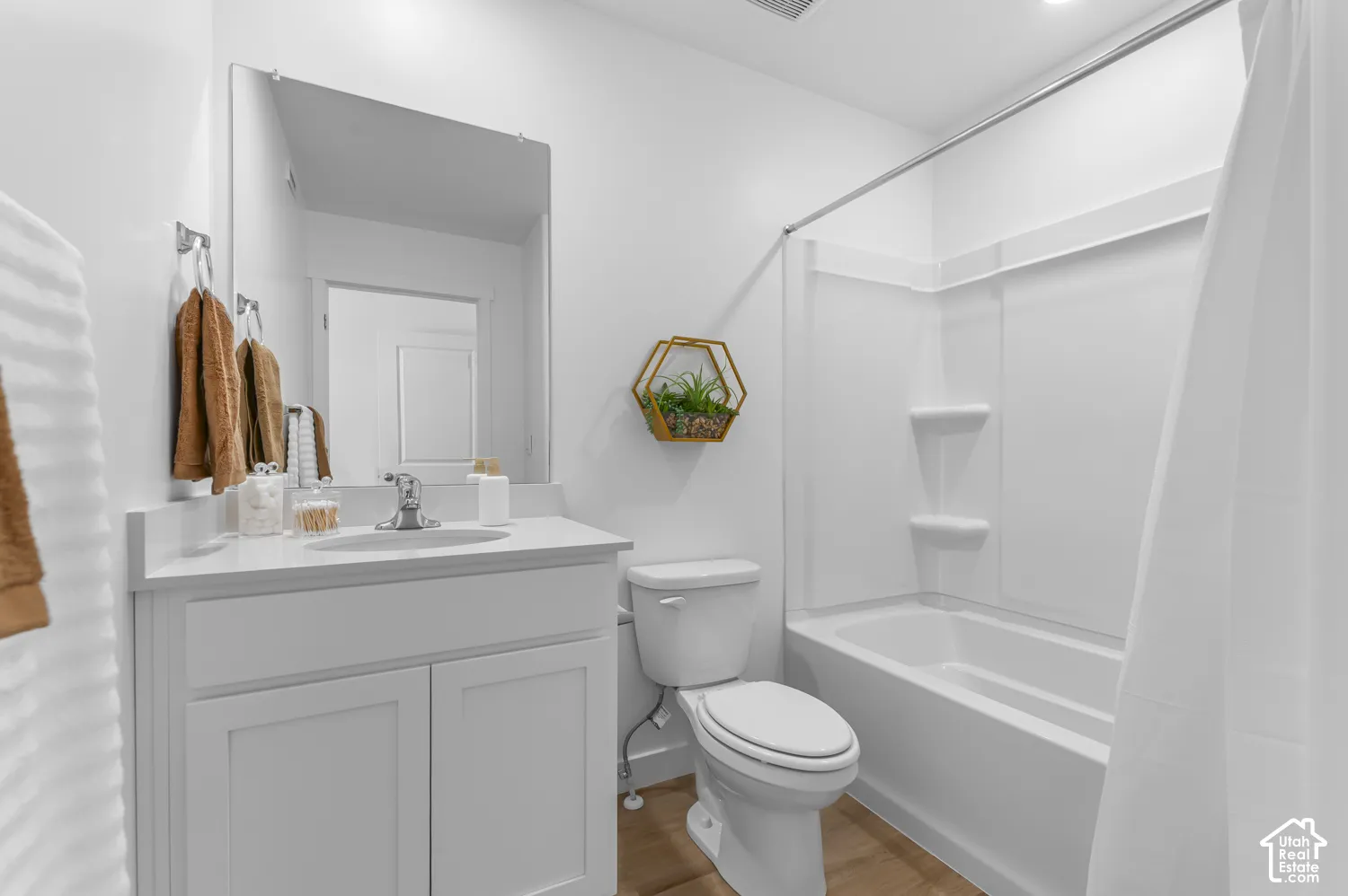 White vanity with a single basin sink, chrome faucet, and rectangular mirror