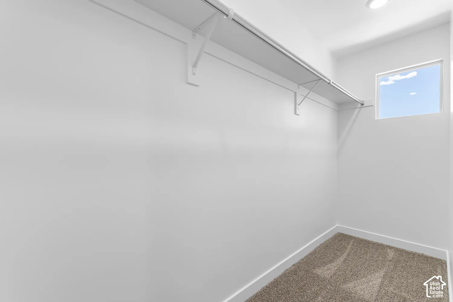 Built-in shelving and hanging rod, recessed lighting, window, and neutral carpeting