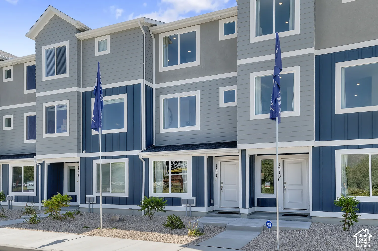 Contemporary multi-level townhome featuring a mixed siding facade, white trim windows, and prominent entryways
