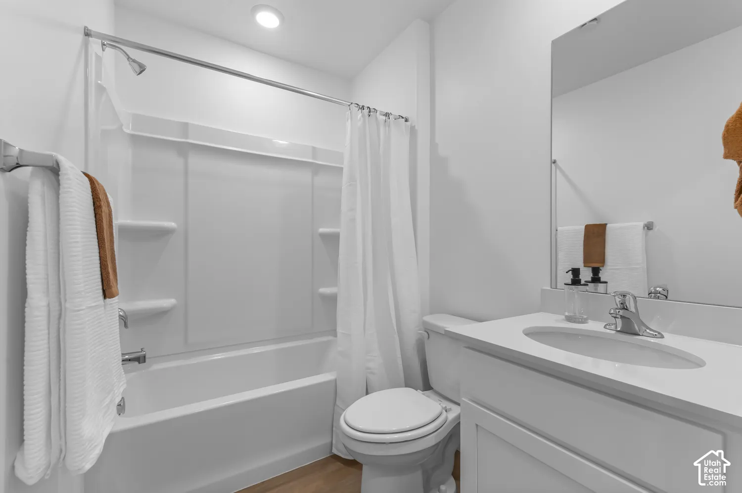 Bathroom with a built-in shower/tub combination, single vanity, and wood-finish flooring